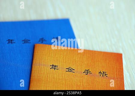 Opuscoli di assicurazione pensionistica giapponese sul tavolo. Libro blu e arancione delle pensioni per i pensionati giapponesi da vicino. Opuscoli di assicurazione pensionistica giapponese su Foto Stock