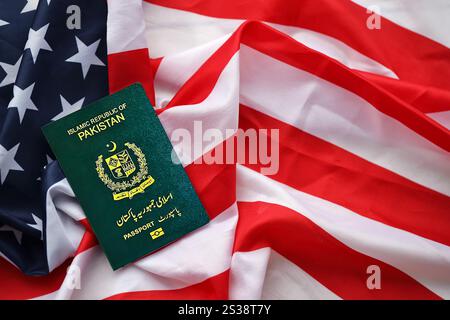 Passaporto verde della Repubblica Islamica del Pakistan sullo sfondo della bandiera nazionale degli Stati Uniti da vicino. Concetto di turismo e diplomazia Foto Stock