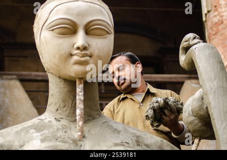 Un esperto artigiano forma meticolosamente l'argilla in una splendida scultura in un vivace laboratorio pieno di creazioni artistiche. La luce calda del sole. Foto Stock