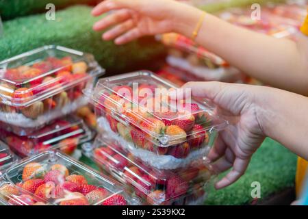 Fragole rosse fresche in donna disposte a mano in cesti pronti per la vendita sul mercato. Messa a fuoco selettiva. Foto Stock