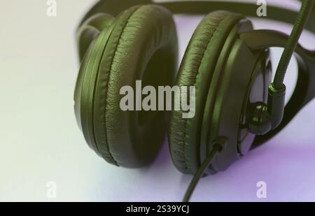 Le cuffie nere si trovano su un colorato sfondo viola pastello. Concetto di ascolto musicale. Concetto di ascolto musicale. Le cuffie nere si appoggiano al viola Foto Stock