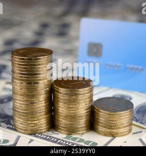 Monete ucraine e carta di credito blu chiudono su una grande pila di banconote da cento dollari. Valuta dell'Ucraina. Saldo del denaro e scambio online Foto Stock