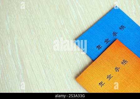 Opuscoli di assicurazione pensionistica giapponese sul tavolo. Libro blu e arancione delle pensioni per i pensionati giapponesi da vicino. Opuscoli di assicurazione pensionistica giapponese su Foto Stock