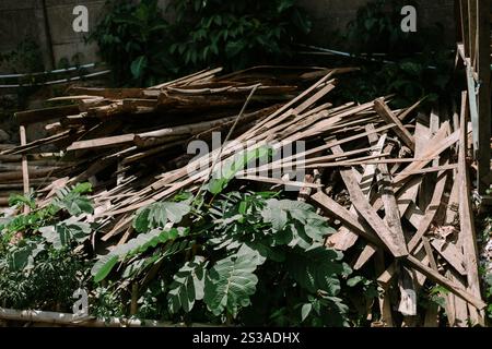 Pila di assi e travi in legno usati, che mostrano trame intemperie e segni di utilizzo precedente, impilati a terra Foto Stock