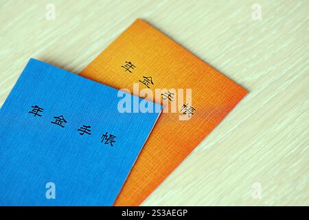 Opuscoli di assicurazione pensionistica giapponese sul tavolo. Libro blu e arancione delle pensioni per i pensionati giapponesi da vicino. Opuscoli di assicurazione pensionistica giapponese su Foto Stock