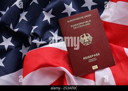 Passaporto tedesco rosso dell'Unione europea sullo sfondo della bandiera nazionale degli Stati Uniti da vicino. Concetto di turismo e diplomazia. Passaporto tedesco rosso di Foto Stock
