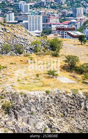 Base rocciosa del complesso Cascade e sopra la vista del quartiere nella città di Yerevan dal Monumento al 50° anniversario nella soleggiata giornata estiva Foto Stock