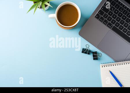 Tazza di caffè, tastiera per computer portatile e blocco note sulla scrivania blu dell'ufficio. Concetto di ufficio aziendale Foto Stock