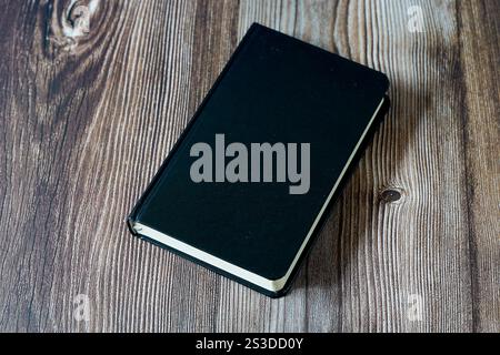 Copertina vuota di un modello di libro nero su sfondo in legno con spazio di testo Foto Stock