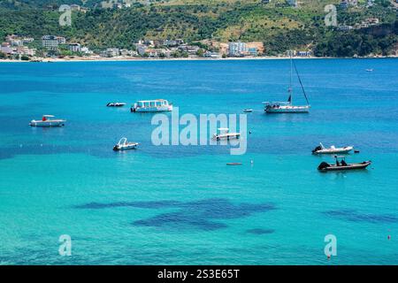 Barche nella baia di Himare sulla costa dell'Albania meridionale, parte della riviera albanese. Situato nella contea di Vlore, si trova tra i monti Ceraunian A. Foto Stock