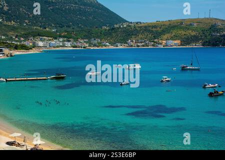 Barche nella baia di Himare sulla costa dell'Albania meridionale, parte della riviera albanese. Situato nella contea di Vlore, si trova tra i monti Ceraunian A. Foto Stock