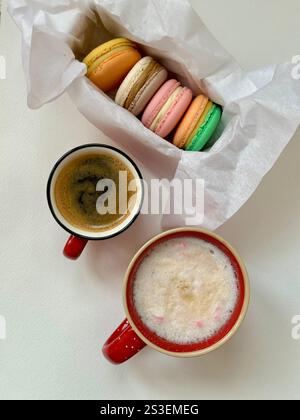 Macaron in diversi colori e gusti nella scatola e nelle tazze di caffè Foto Stock