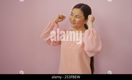 Donna che festeggia su sfondo rosa, vestita con camicetta rosa chiaro, mostra gioia e sicurezza, mostra bellezza e vivacità con un allegro espr Foto Stock