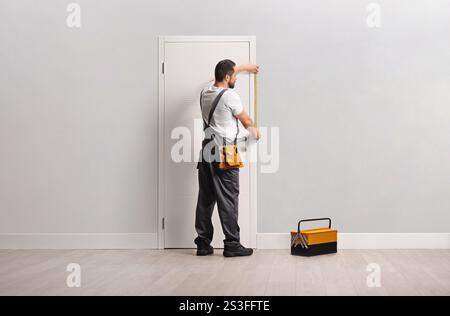 Falegname che misura la porta di un appartamento Foto Stock