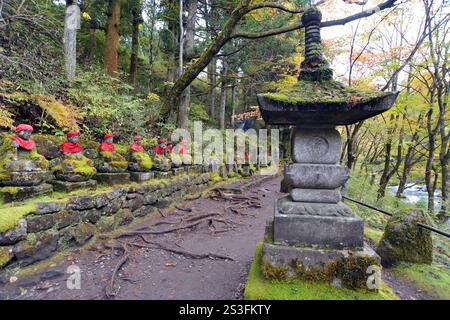 Le statue buddiste indossano bavaglino rosso nel Parco Nazionale di Nikko, in Giappone, per proteggere i viaggiatori e sono custodi dei bambini in questa area del Patrimonio Nazionale Foto Stock