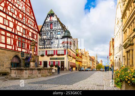La Fontana di San Giorgio accanto a pittoreschi edifici in legno nella piazza centrale del mercato Marktplatz a Rothenburg ob der Tauber, Germania. Foto Stock