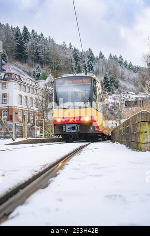 Tram su piste innevate in un paesaggio invernale con alberi ed edifici, Bad Wildbad, Foresta Nera, Germania, Europa Foto Stock