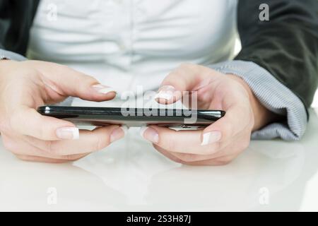 Una donna scrive un messaggio di testo su un telefono cellulare. Comunicazione veloce tramite telefono cellulare. Austria Foto Stock