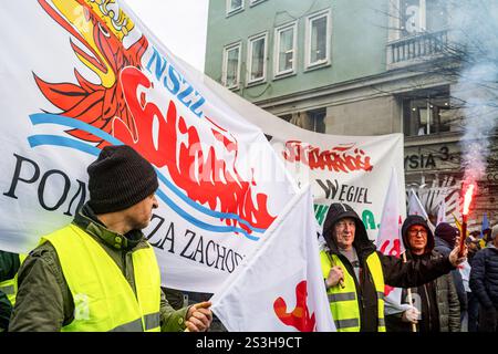 Varsavia, Polonia. 9 gennaio 2025. Davanti agli striscioni, un manifestante tiene un bagliore acceso durante la manifestazione. I lavoratori dell'energia, in particolare i minatori di carbone, aderenti all'unione di solidarietà, hanno marciato attraverso Varsavia dalla sede del gruppo polacco per l'energia al ministero dei beni statali. La manifestazione è stata indetta dopo che il governo ha preso la decisione di chiudere le centrali elettriche a carbone in Slesia. Gli organizzatori hanno dichiarato che combatteranno questa decisione e allo stesso tempo lotteranno per l'elettricità più economica nelle case polacche. Credito: SOPA Images Limited/Alamy Live News Foto Stock