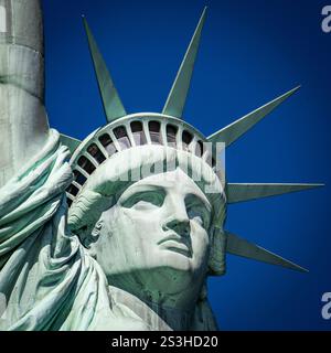 La Statua della libertà sorge su Liberty Island, un faro di libertà e speranza. Splendida luce che cattura la sua maestosità sullo sfondo del cielo blu. Foto Stock