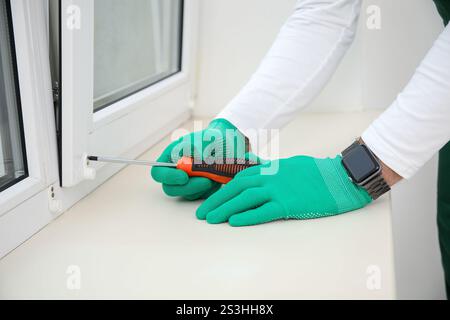 Lavoratore maschio che avvitava la finestra in camera, primo piano Foto Stock