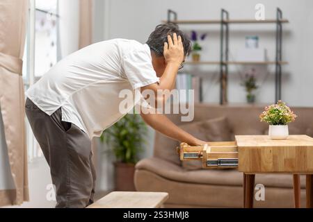 Uomo anziano asiatico che trova qualcosa che l'ha dimenticato nei cassetti. Foto Stock