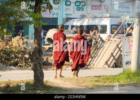 Due monaci buddisti camminano attraverso una strada trafficata in Myanmar Foto Stock