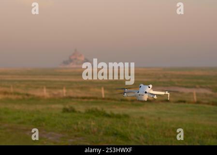 Un drone vola su campi coltivati e alberi con Mont Saint-Michel sullo sfondo in Normandia, Francia Foto Stock