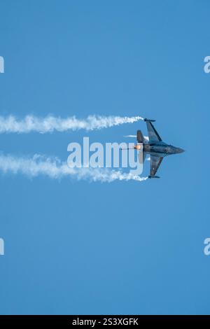 Caccia F-16 che esegue una manovra audace nel cielo. sentiero del fumo. Foto Stock