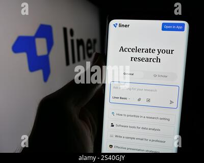 In questa illustrazione fotografica, una persona ha in mano uno smartphone con sullo schermo la pagina Web dell'azienda statunitense di intelligenza artificiale Liner Inc. Con il logo. Foto Stock