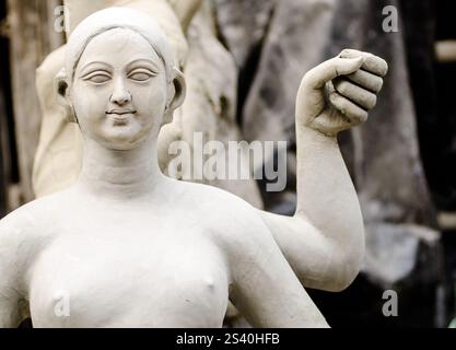 Un esperto artigiano forma meticolosamente l'argilla in una splendida scultura in un vivace laboratorio pieno di creazioni artistiche. La luce calda del sole. Foto Stock