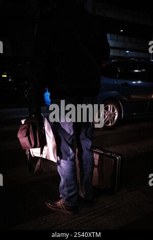 Uomo nel traffico stradale nel porto del Pireo di notte ad Atene capitale della Grecia nella regione Attica il 13 gennaio 2024. Homme dans la circul Foto Stock