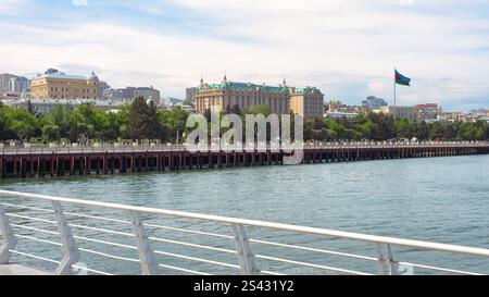 Baku, Azerbaigian - 10 maggio 2024: Giornata vivace sul lungomare, con viale Baku, skyline della città e una maestosa bandiera esposta con orgoglio. Le persone passeggiano lungo la passeggiata godendosi l'atmosfera Foto Stock