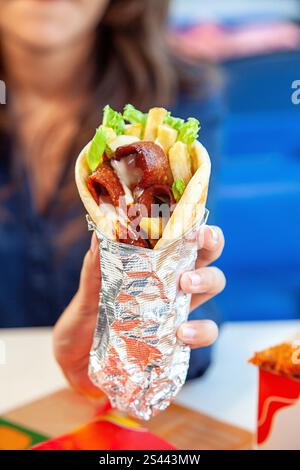 Il manzo di prima qualità, tagliato a fette sottili, avvolge il pane pita tenendo in mano la donna. Foto Stock