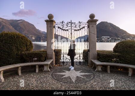 Il cancello del Parco Ciani che si affaccia sul Lago di Lugano al tramonto, in Svizzera, con una donna che ammira il panorama Foto Stock