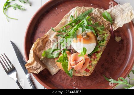 Bruschetta con avocado, salmone salato, microgreen e uova in camicia, vista dall'alto Foto Stock