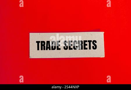 Messaggio segreto commerciale scritto su carta con sfondo rosso. Simbolo dei segreti commerciali concettuali. Copia spazio. Foto Stock