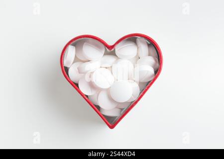 Il cuore è fatto di pillole bianche su sfondo bianco. Pillole medicinali e capsule per la salute, integratori alimentari e vitamine per la salute del cuore e un Foto Stock