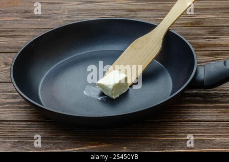 Padella con un pezzo di burro su fondo di legno Foto Stock