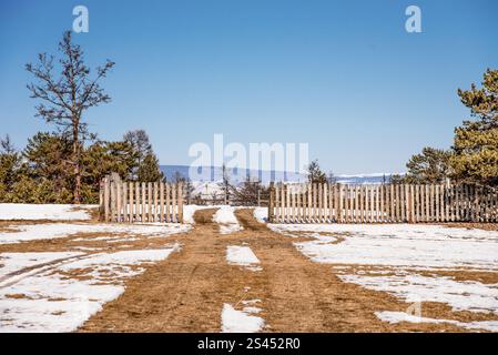 Strada di campagna per auto nei sobborghi, piccola casa privata con recinzione, limpida giornata invernale Foto Stock