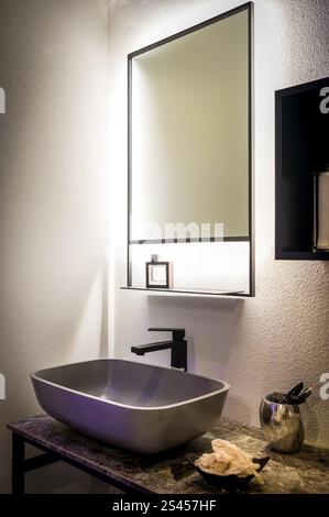 Interni di un bagno moderno con specchio illuminato, elegante lavabo ed elementi di design contemporaneo Foto Stock