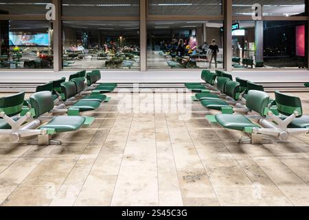 Sedie verdi vuote all'interno della sala d'attesa dell'aeroporto internazionale vicino al cancello di notte Foto Stock