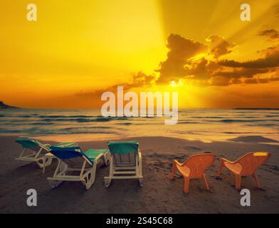 Vista sul mare la sera. Spiaggia con chaise longue al tramonto dorato Foto Stock