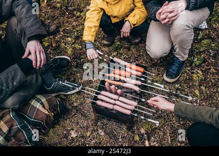 Camping Camp Kitchen, Travelers Cooking Food in pentole su un fuoco da campeggio, Tourist Friying Sausages Foto Stock