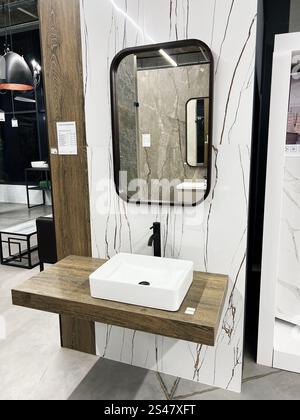 Kiev, Ucraina - 10 gennaio 2025: Un bagno dal design elegante e contemporaneo con lavabo rettangolare su un ripiano in legno, abbinato a una grande m Foto Stock