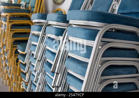 Vista ravvicinata di molte sedie blu sovrapposte nella sala banchetti. Foto Stock