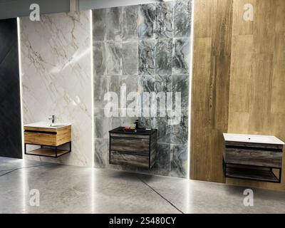 Kiev, Ucraina - 10 gennaio 2025: Moderno display per il bagno con molteplici tessuti piastrellati e lavandini sospesi in legno con lavandini sotto l'ambiente Foto Stock