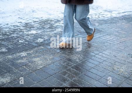 Prodotti chimici antigelo. Donna che cammina per strada trattata con sale tecnico o prodotti chimici antighiaccio Foto Stock