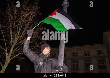 Un manifestante sale su un lampione e sventola una bandiera palestinese durante la manifestazione. La sera del 10 gennaio, attivisti e manifestanti filo-palestinesi si riuniscono presso la Cancelleria del Presidente polacco per protestare contro la recente decisione del governo polacco di estendere l'immunità dal mandato d'arresto della Corte penale internazionale a Benjamin Netanyahu, in occasione del 80° anniversario della liberazione di Auschwitz. I manifestanti marciano dalla Cancelleria all'ufficio del primo Ministro chiedendo la rimozione di qualsiasi proposta di immunità per il leader israeliano. Foto Stock