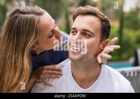 Coppia allegra che applica crema solare o scrub esfoliante all'aperto Foto Stock